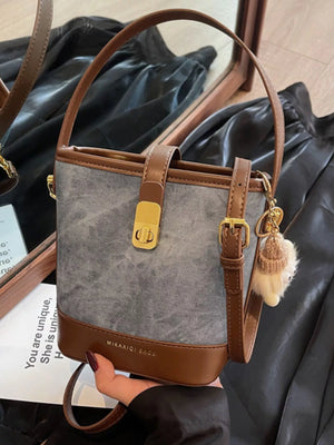 Elegant bucket bag in grey denim-look fabric with brown PU leather trim and gold hardware.