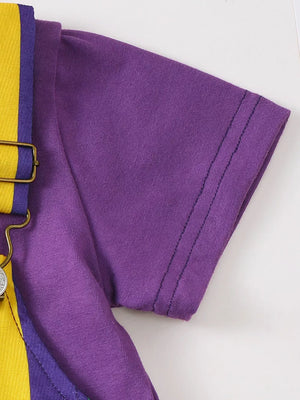 Purple tee with yellow and purple striped overalls, showing strap detail.