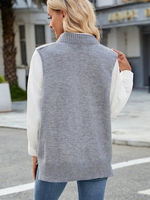 Gray cable knit sweater vest with ribbed collar and hem, worn over a white shirt.