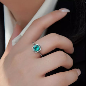 Elegant sterling silver ring with a round teal zircon surrounded by small clear stones.