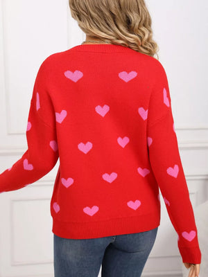 Red acrylic sweater with pink heart print, crew neck, long sleeves, and ribbed trim.