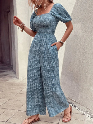 Smocked bodice floral wide-leg jumpsuit in dusty blue with puff sleeves and square neckline.