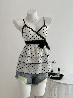 White polka dot camisole with black lace trim, tiered ruffles, and black bow detail.