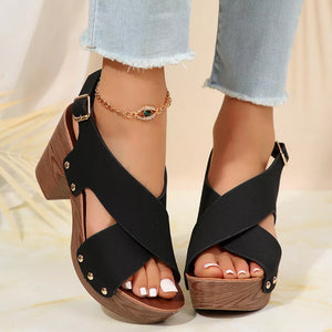 Black crisscross high heel sandals with wood-look block heel and stud details.