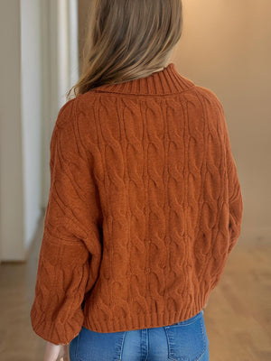 Oversized caramel cable knit turtleneck pullover sweater with ribbed collar and cuffs.