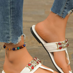 White jeweled toe-post flat sandals with red and clear gem embellishments.