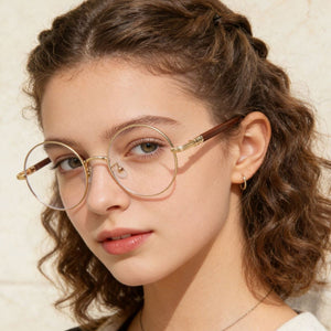 Round frame glasses with gold metal and brown acetate temples, clear lenses.