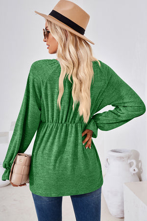 Green long sleeve blouse with cinched waist and balloon sleeves.