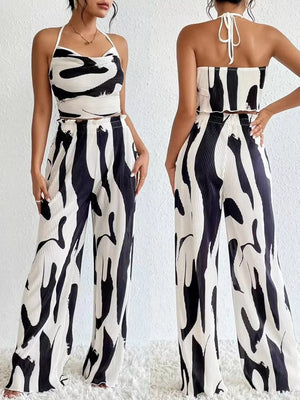 Chic abstract print crop top and pants set in black and white polyester with halter neck and wide leg pants.
