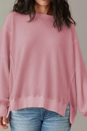 Dusty pink waffle knit pullover sweater with slit sleeves and raw hem.