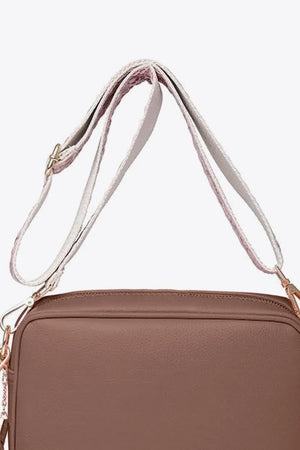 Textured crossbody bag in brown with a patterned strap and tassel detail.