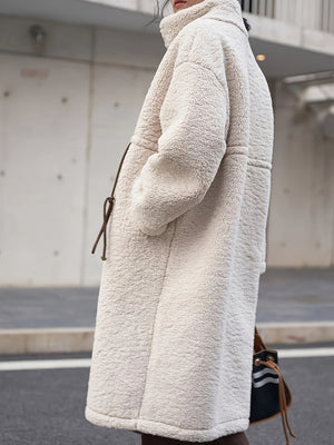 Oversized beige sherpa overcoat with suede tie detail and pockets.
