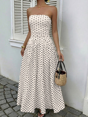 White polka dot strapless maxi dress with a belted waist and A-line skirt.