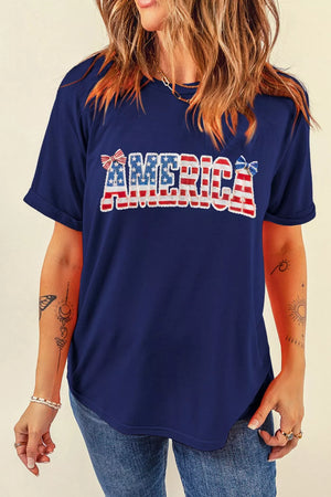 Navy patriotic graphic t-shirt with "AMERICA" text and bow details, crew neck, short sleeves.