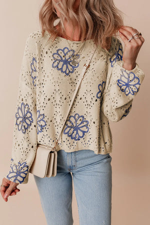 Beige eyelet knit pullover with blue floral embroidery and long sleeves.