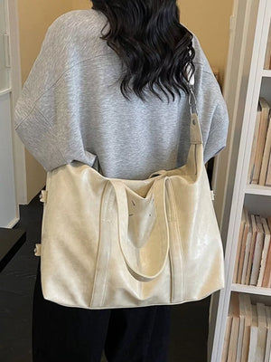 Distressed vintage leather travel bag in cream white with double handles and a shoulder strap.