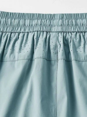 Men's turquoise drawstring active pants with elastic waistband and perforated detail.