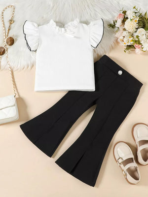 White ruffle-sleeve top with black trim and black flare pants with side slits.