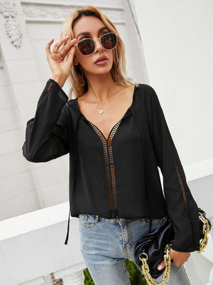 Black lace-inset blouse with slit sleeves and tie-neck detail.