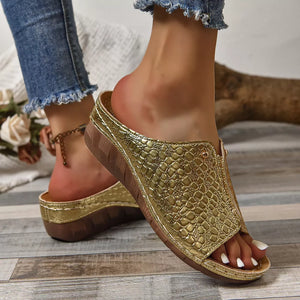 Gold glossy crocodile-embossed wedge sandals with open toe and comfortable platform sole.