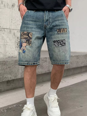 Men's denim shorts with graphic patchwork details and a distressed wash.