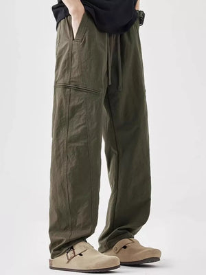 Olive green men's wide-leg sweatpants with drawstring and zip pocket detail.
