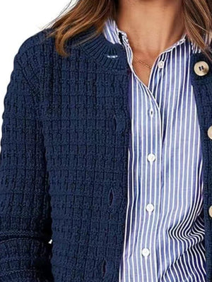 Navy textured knit button-up cardigan with cream buttons, styled over a blue striped shirt.
