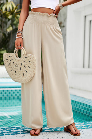 Tan smocked waist palazzo trousers with wide legs and a ruffled hem.