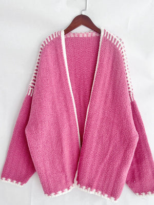 Pink oversized knit cardigan with white contrast stitching and open front.