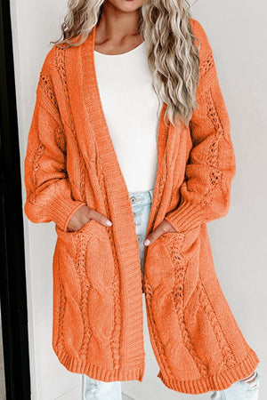 Burnt Coral cable knit open-front cardigan with pockets and textured sleeves.