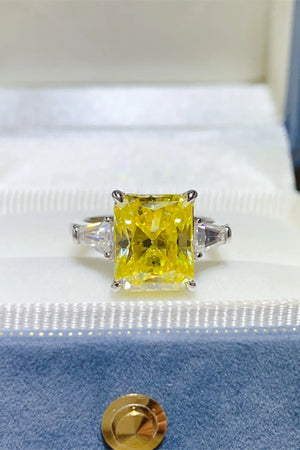 Canary yellow emerald cut ring with side trapezoid stones in a silver setting.