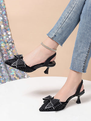 Black slingback heels with rhinestone bowknot detail and pointed toe.