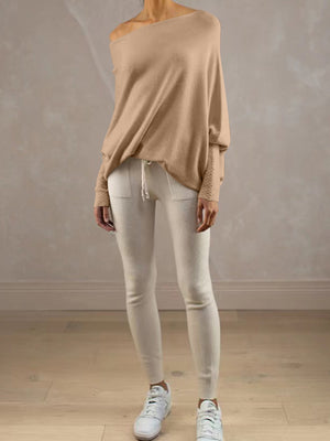 Off-shoulder drape knit sweater in cream with textured cuffs, paired with cream leggings.