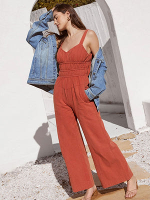 Orange-red tie-strap bodice wide-leg jumpsuit with smocked waist and pockets.