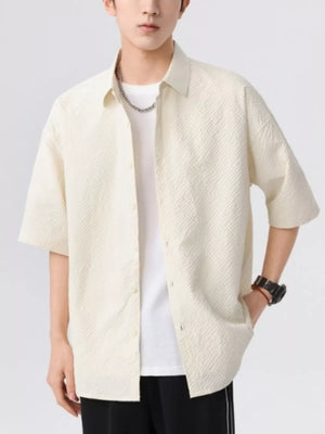 Men's beige textured short-sleeve button-up shirt with a white t-shirt underneath.