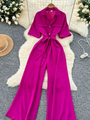 Belted wide-leg jumpsuit in pink with short sleeves and buttoned pockets.