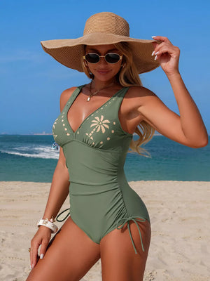 Army green one-piece swimsuit with V-neck, palm tree print, and adjustable drawstring sides.