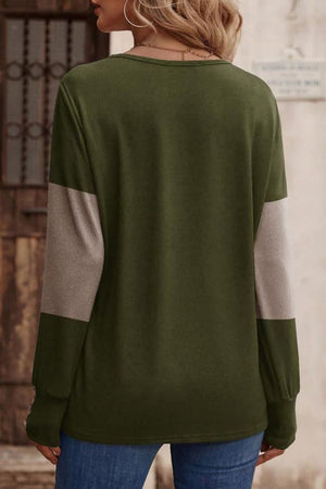 Green knit top with taupe colorblock sleeves and button cuffs.