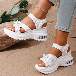 White textured open-toe wedge sandals with adjustable straps and air cushioning detail.
