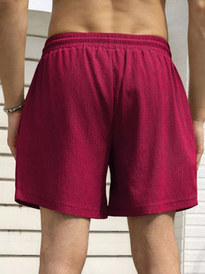 Men's burgundy drawstring chino shorts with textured fabric and elastic waistband.