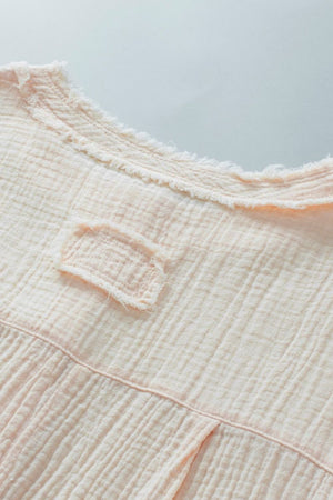 Beige textured gauze henley blouse with raw edge neckline and chest detail.