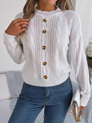 White cable knit button-up sweater with brown buttons and a mock neckline.