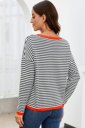Striped crewneck sweater with contrast orange trim and long sleeves.