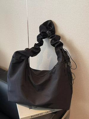 Black ruched nylon shoulder bag with zipper detail and drawstring accents.