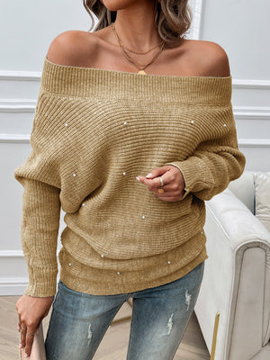 Off-the-shoulder tan knit sweater with pearl embellishments and long sleeves.