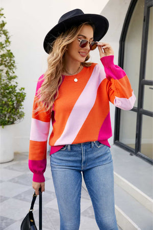 Diagonal colorblock knit sweater in orange and pink acrylic with crew neck and long sleeves.