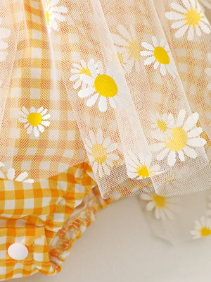 Yellow gingham baby one-piece with daisy-print tulle overlay and ruffle trim.
