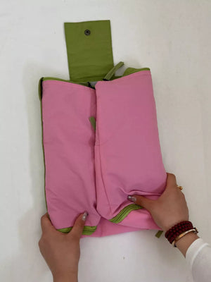 Pink and green two-tone nylon travel bag with snap closure detail.