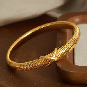 Gold ribbed bangle bracelet with X-detail clasp