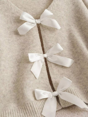Khaki V-neck cardigan with three white satin bow details down the front.